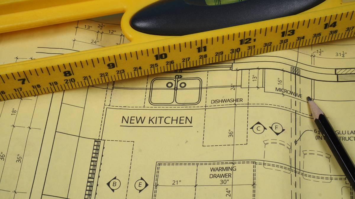 Kitchen remodel blueprint with measuring tape and pencil, showing permit planning and design.